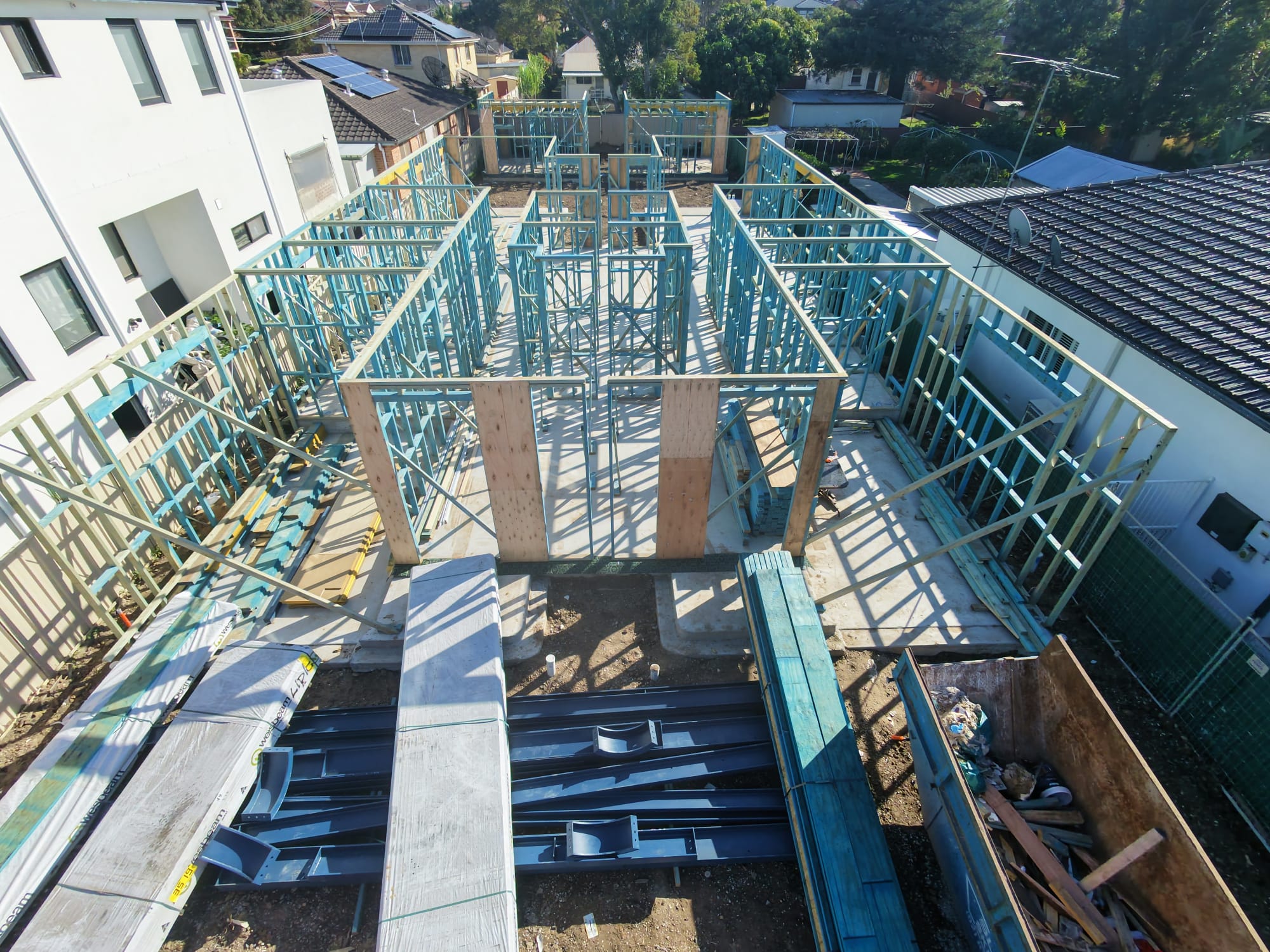 Timber wall frames erected on a slab with structural steel beams laid out ready for install