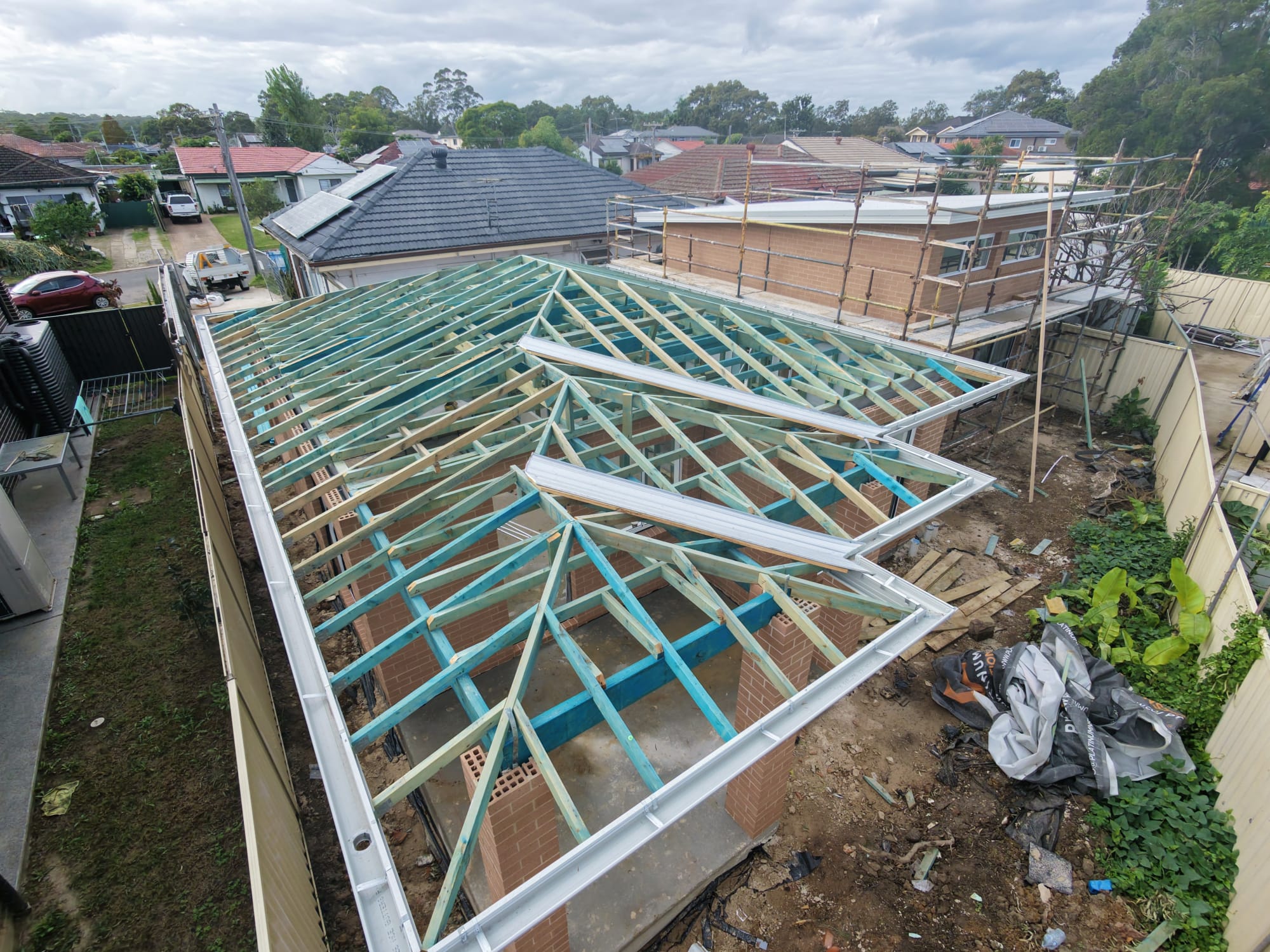 Hip roof timber frame with steel beams and fascia over a brick residence